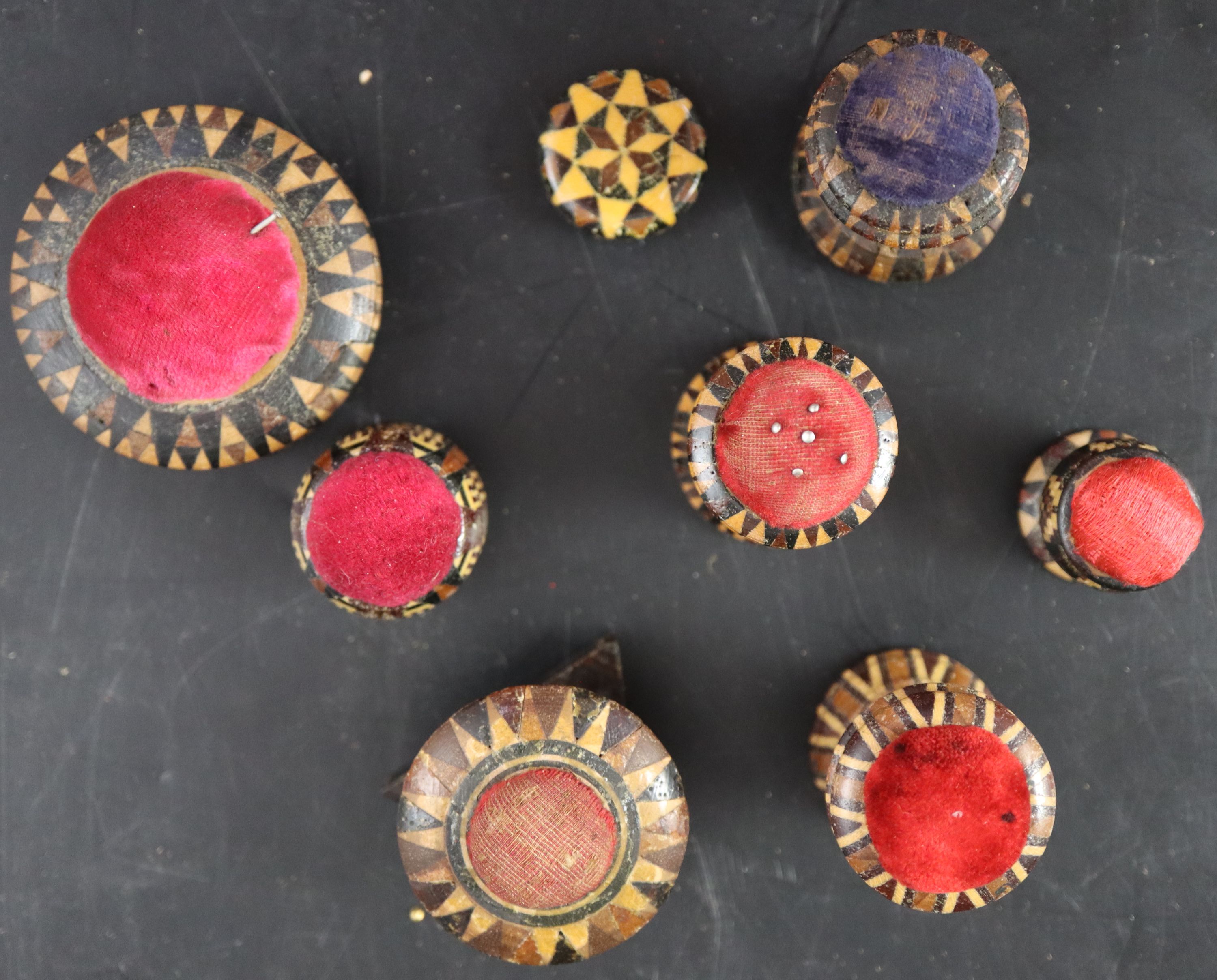 Seven assorted Victorian Tunbridgeware pin cushions and a small spool